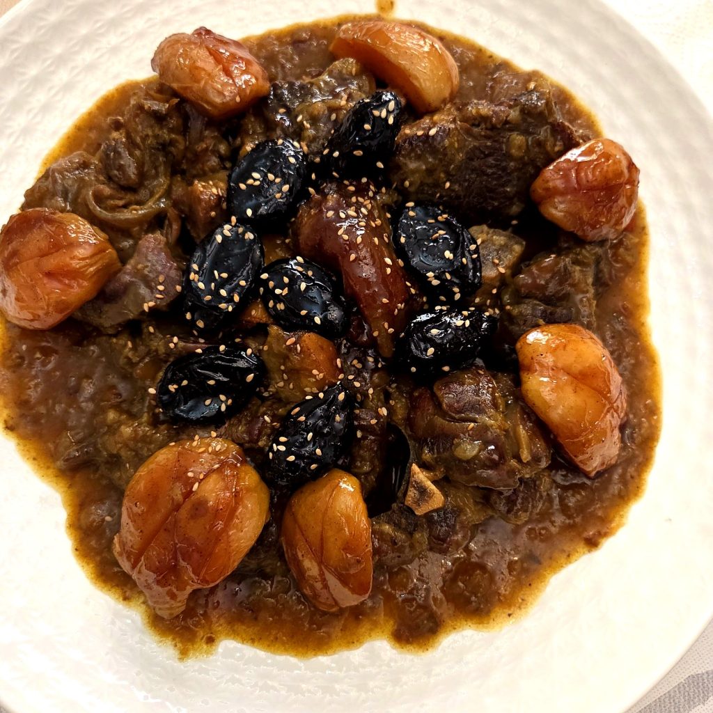Tajine de viande aux pruneaux et fruits secs, parsemé de graines de sésame.
