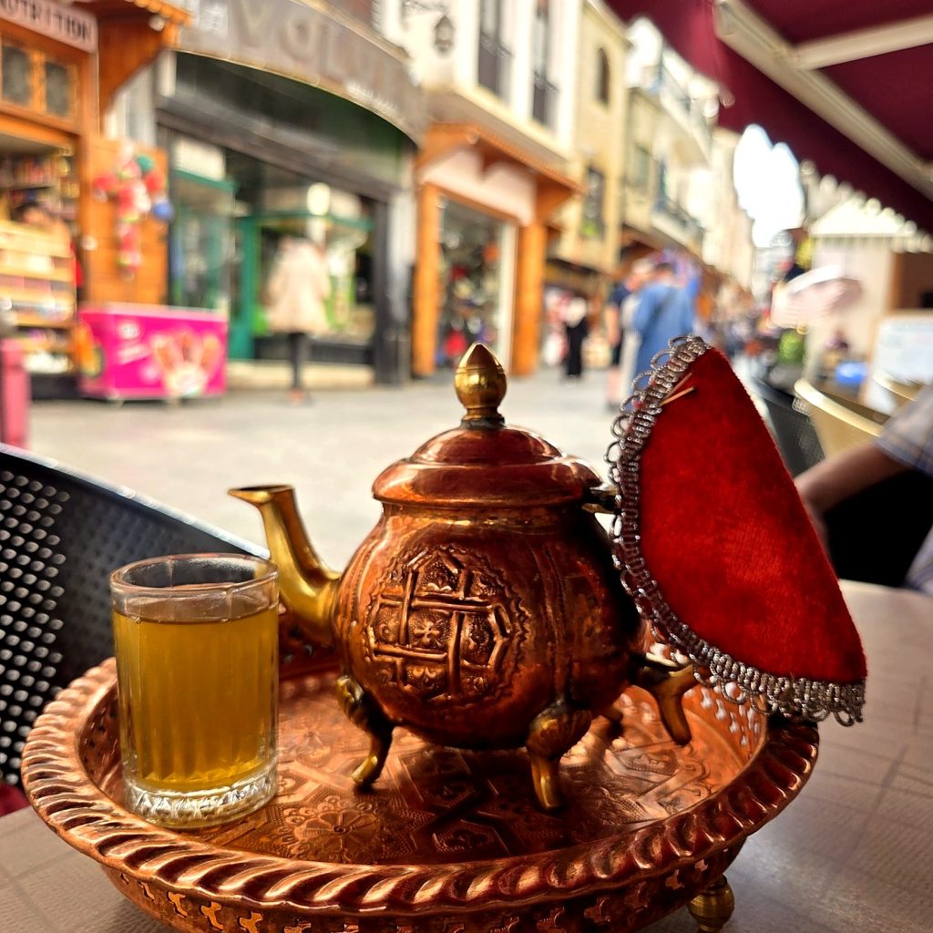 Théière en cuivre et verre de thé à la menthe sur une terrasse de Tanger